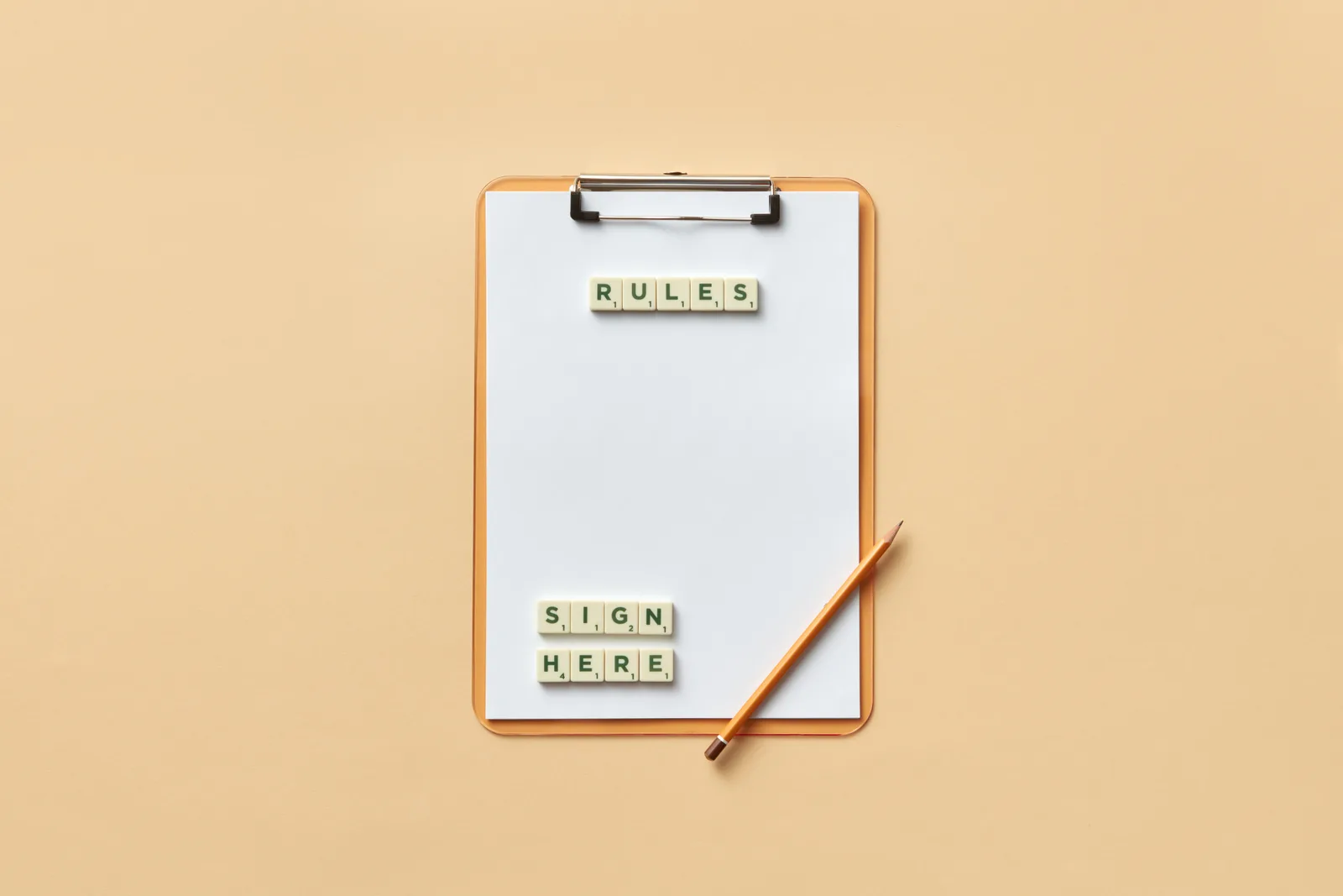 Flat lay of clipboard with letter tiles spelling 'rules' and 'sign here', accompanied by pencil on beige background. Athlete lookalikes submission rules: what contest desks check first