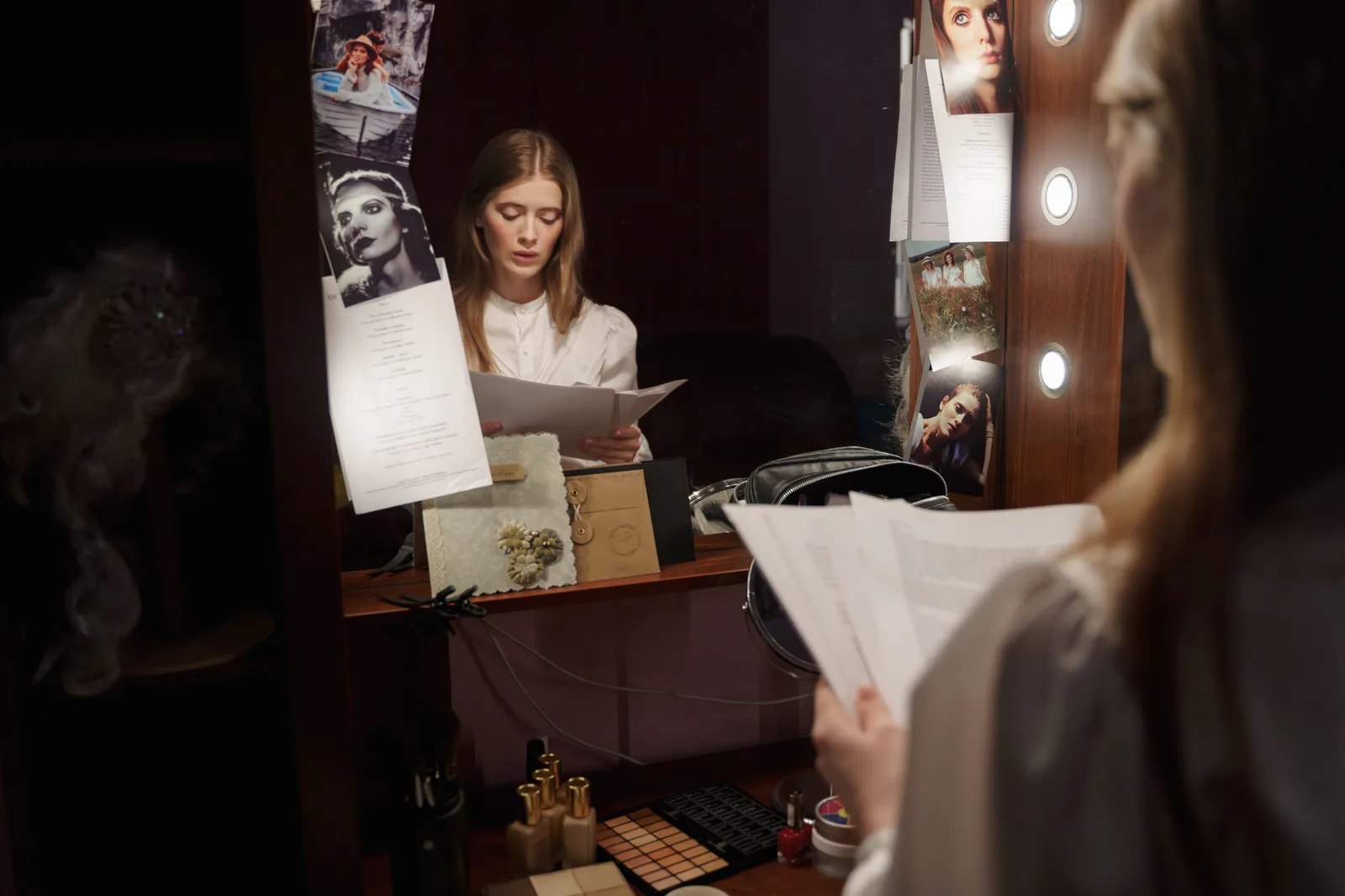 An actress reviews her script in front of a mirror backstage with thoughtful expression. Orlando theme-park lookalike hiring cycles and seasonal pay